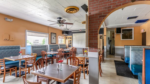 Un restaurante con cabinas, mesas y un ventilador de techo.
