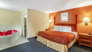 Una habitación de hotel con una cama grande, una bañera roja y dos lámparas de noche.
