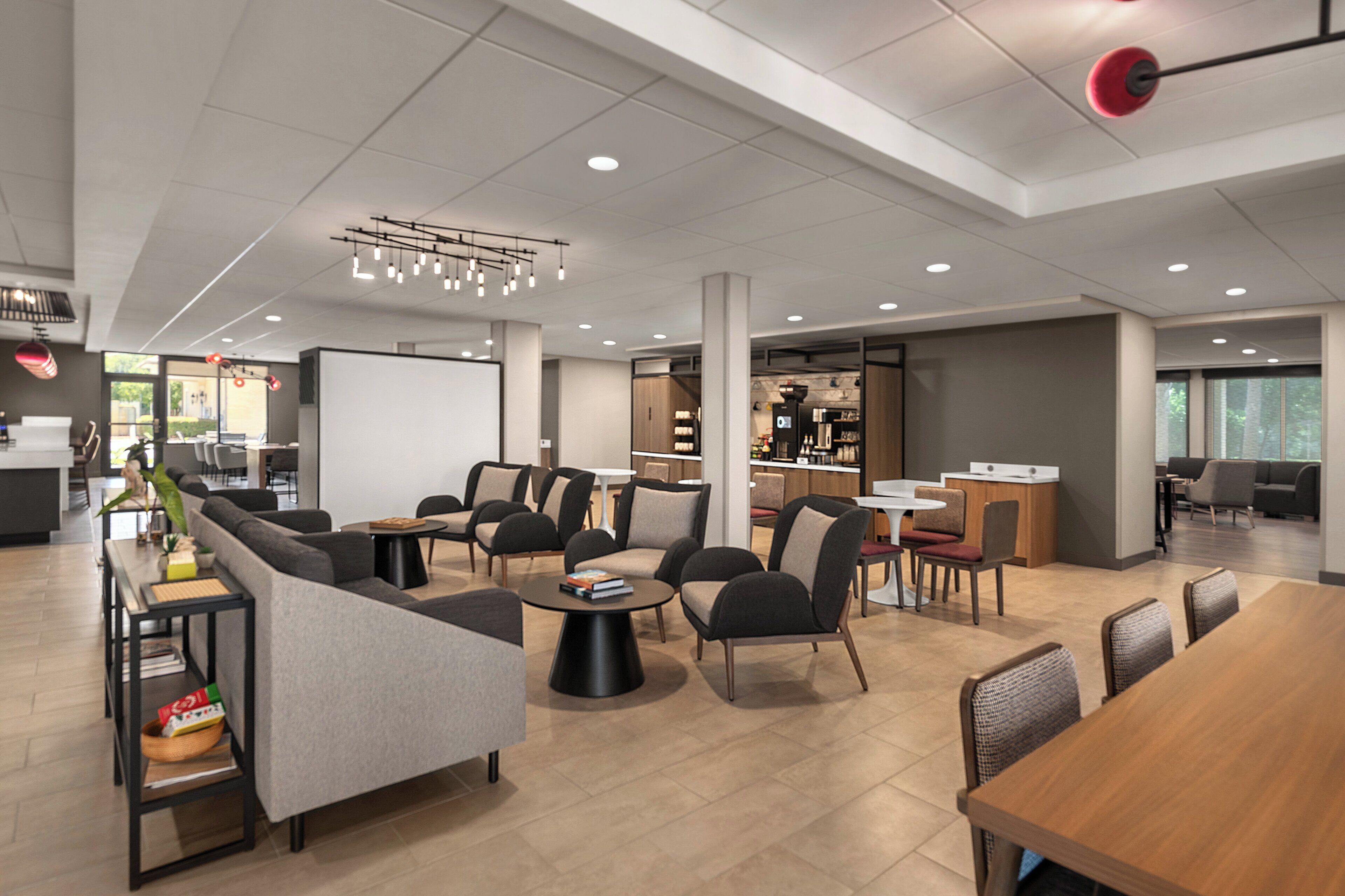 Uma área de estar moderna com sofás, mesas e um bar.