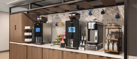 Um espaço para café com várias máquinas de café, um dispensador de água e uma variedade de xícaras e canecas expostas em prateleiras.