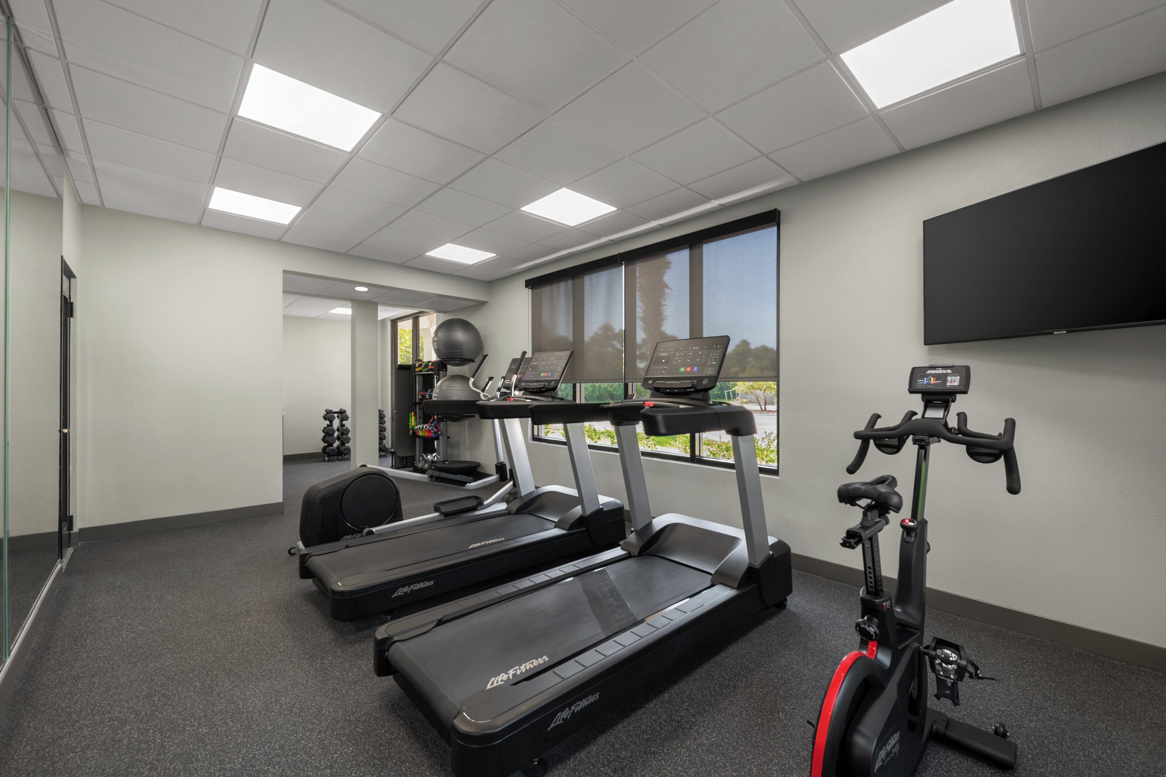 Une salle de remise en forme équipée de tapis de course, d’un vélo d’appartement et d’un rameur.