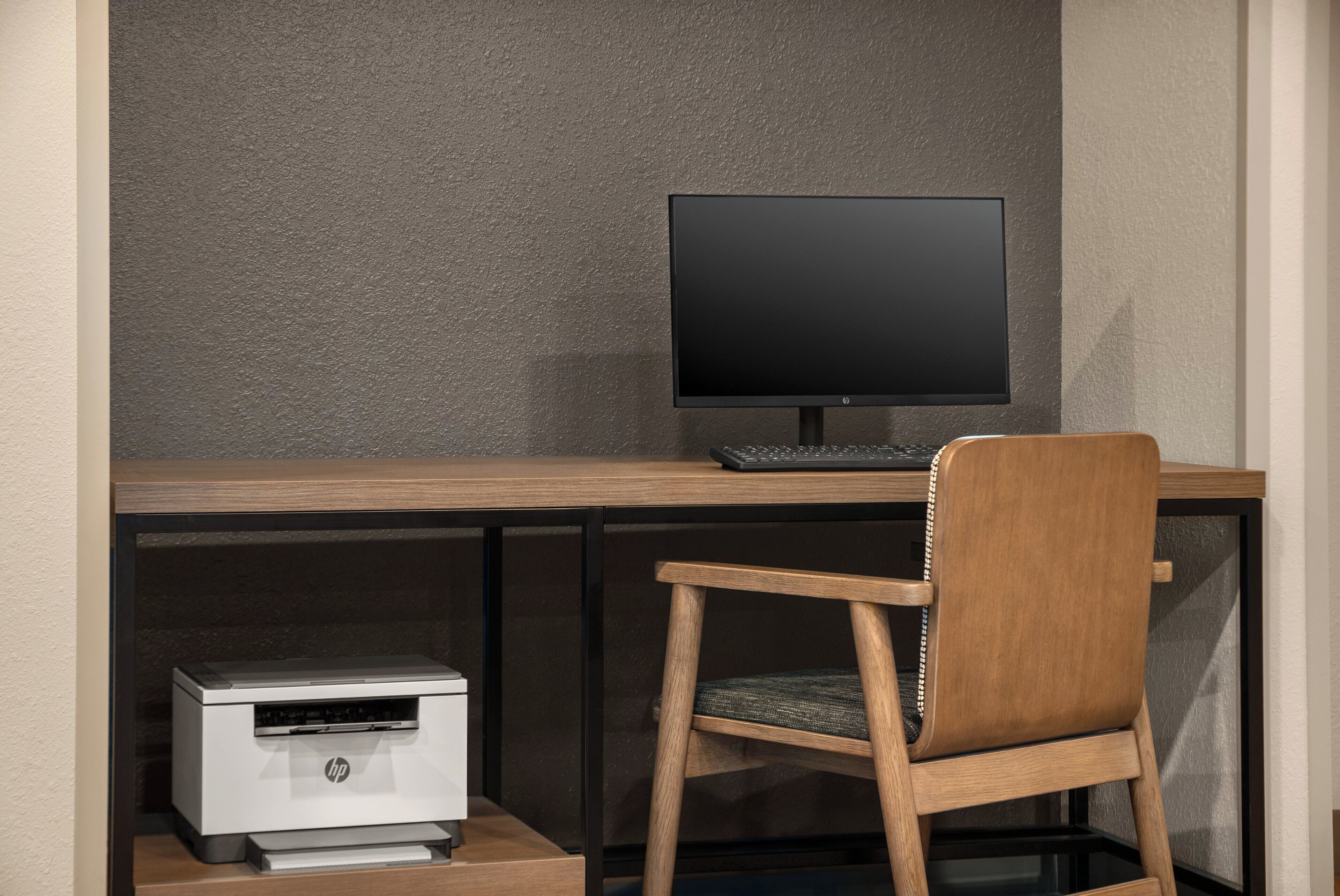 Un espacio de trabajo con un monitor de computadora, teclado e impresora HP sobre un escritorio.