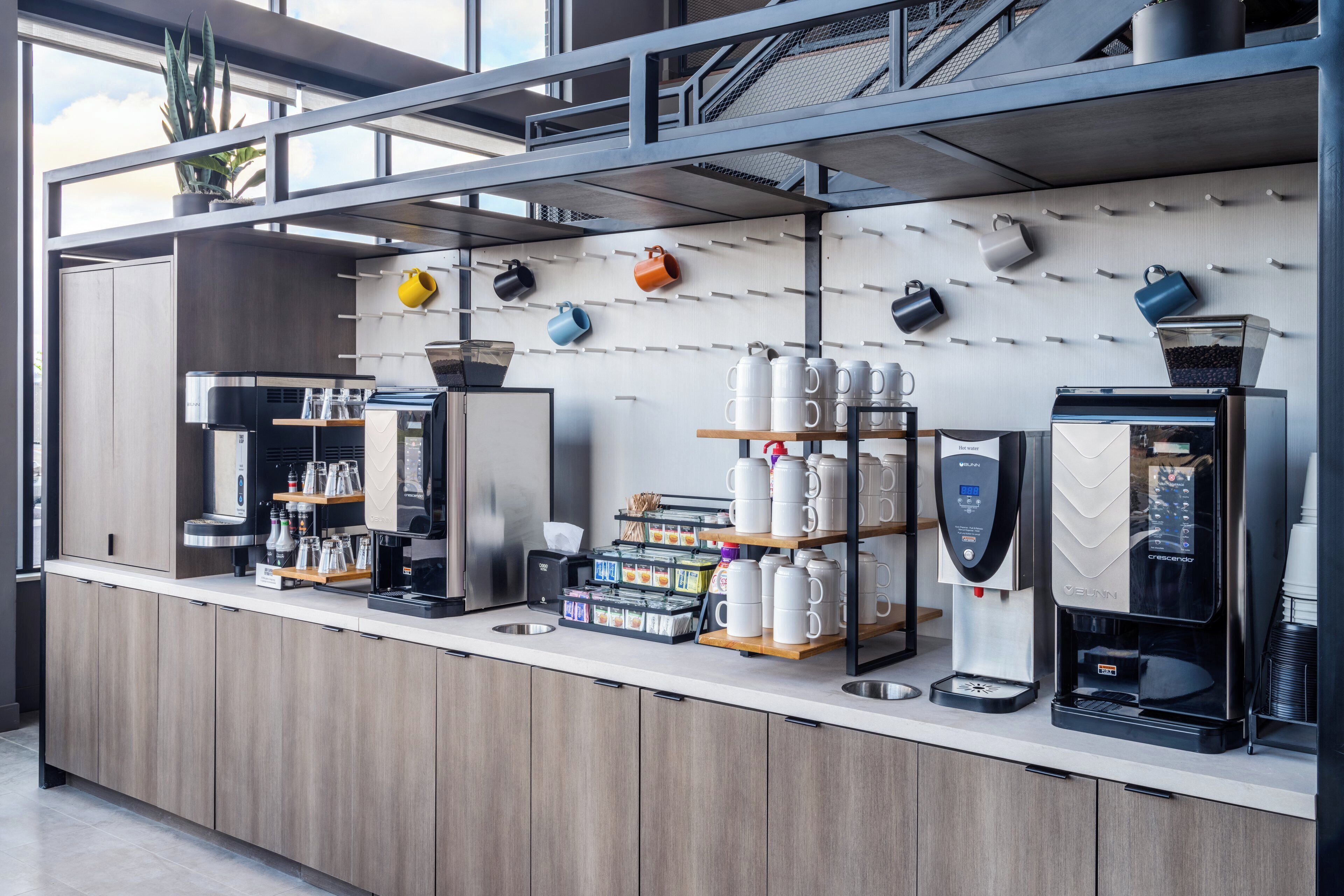 En moderne kaffestation med flere kaffemaskiner, et udvalg af kaffekapsler og forskellige krus.