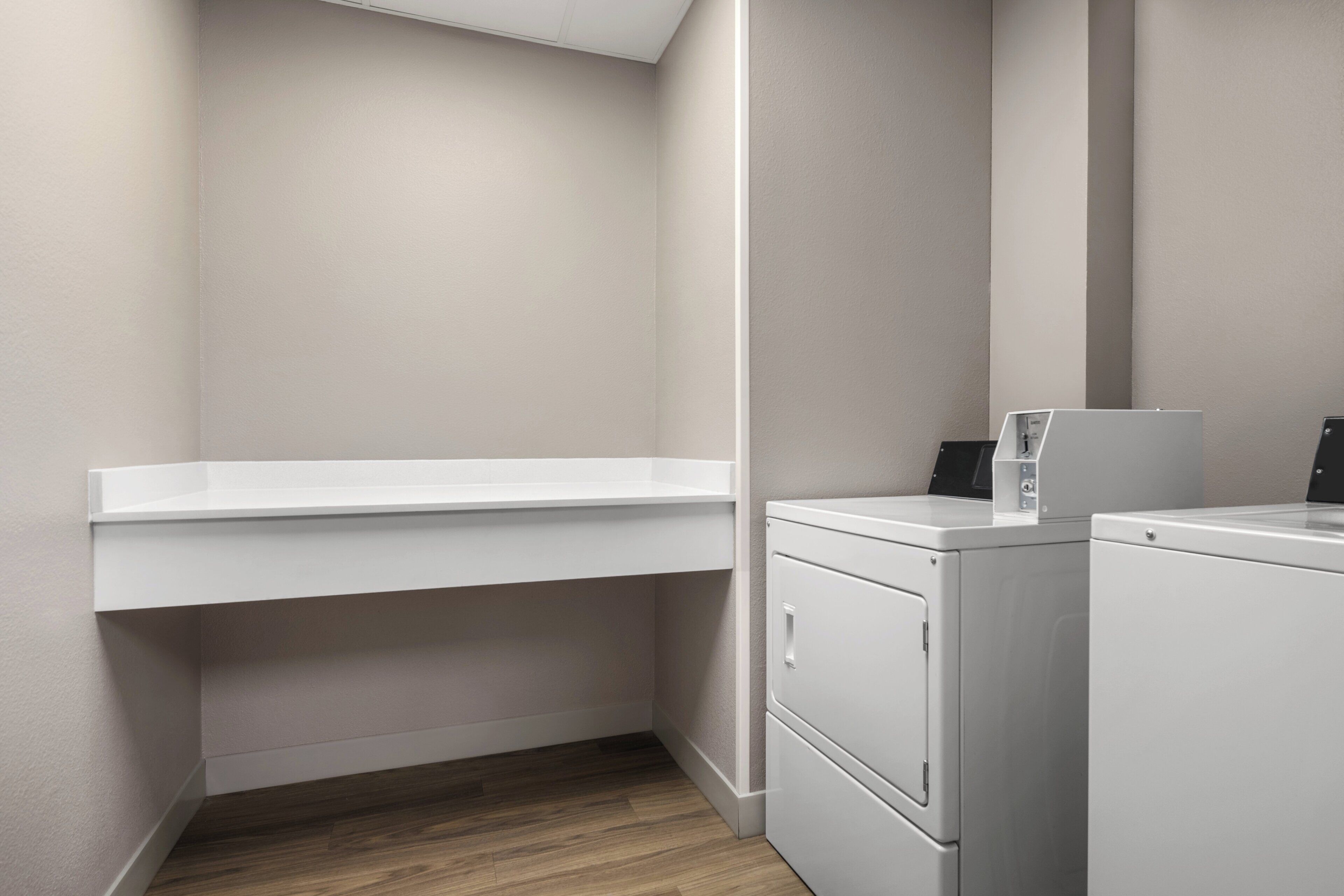 A laundry room with a white washing machine, a dryer, and a white shelf.