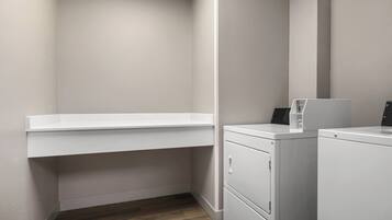 A laundry room with a white washing machine, a dryer, and a white shelf.