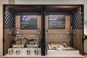 A breakfast buffet with two sections labeled 'hot' and 'not,' featuring various food items and condiments. - Atwell Suites Panama City Beach Southeast by IHG (Panama City Beach)