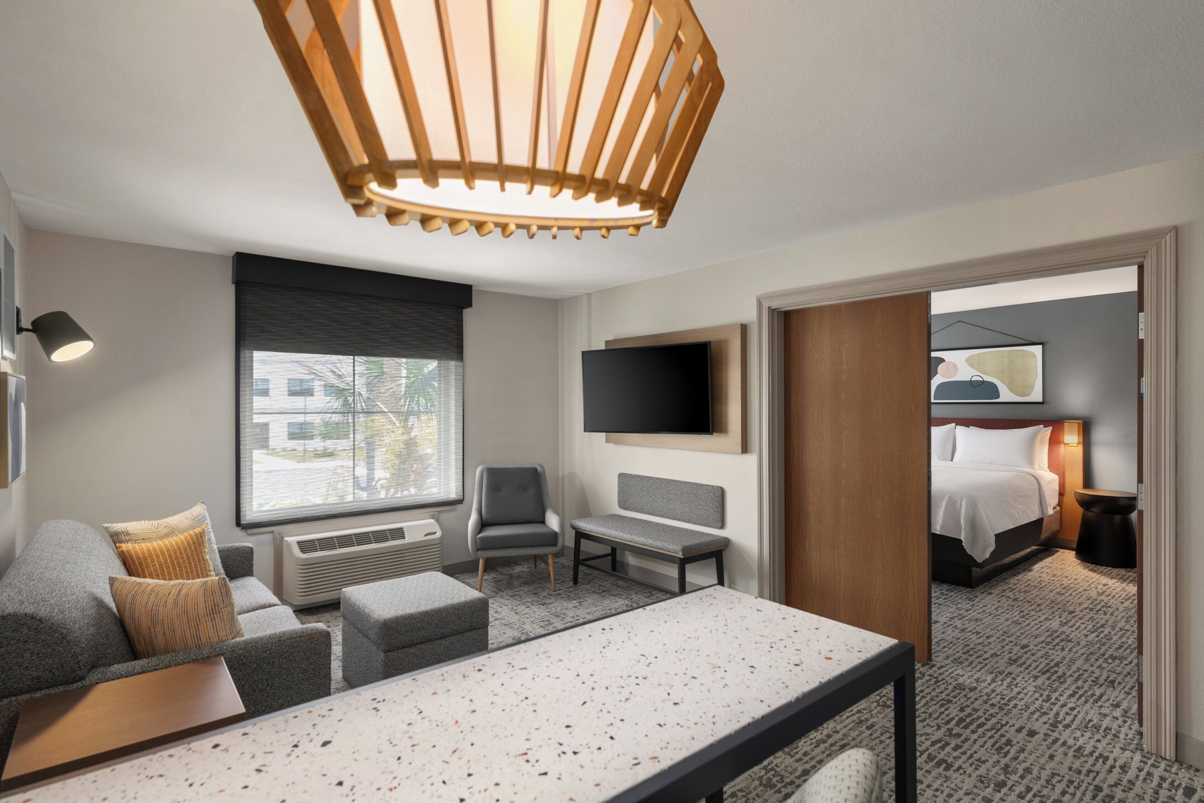 Moderni hotellihuone, jossa on suuri sänky, työpöytä, tuoli, sohva ja televisio.