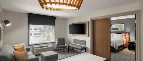Ein modernes Hotelzimmer mit einem großen Bett, einem Schreibtisch, einem Sessel, einer Couch und einem Fernseher.