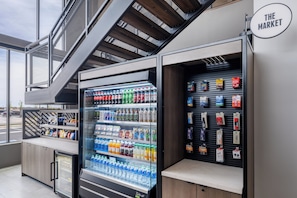 A vending machine area with a variety of drinks and snacks, a refrigerated display case, and a sign reading 'THE MARKET'. - Atwell Suites Panama City Beach Southeast by IHG (Panama City Beach)