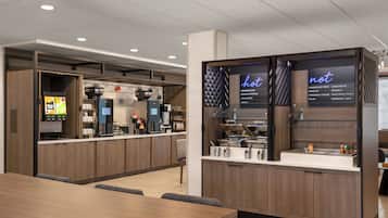 A modern breakfast bar with a coffee machine, tea station, and a menu display.