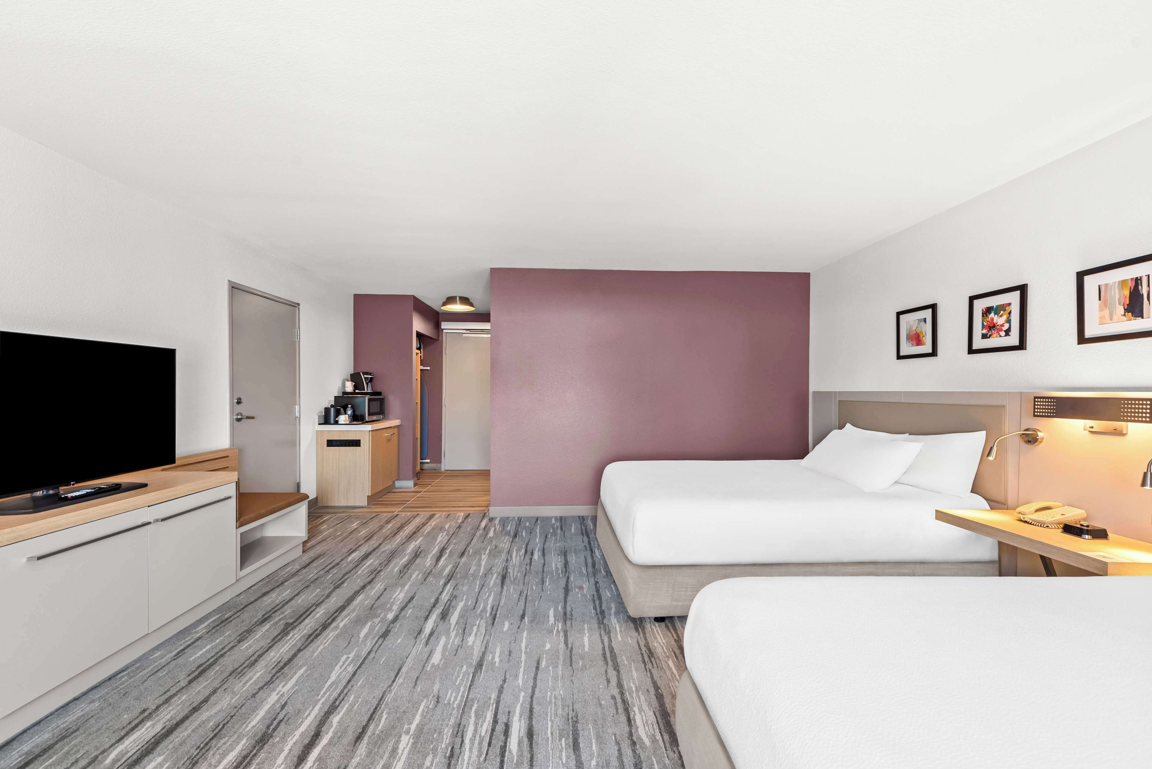 Une chambre d’hôtel avec deux lits, une télévision, un bureau et une kitchenette.