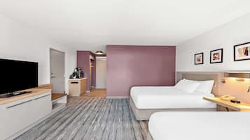 Une chambre d’hôtel avec deux lits, une télévision, un bureau et une kitchenette.