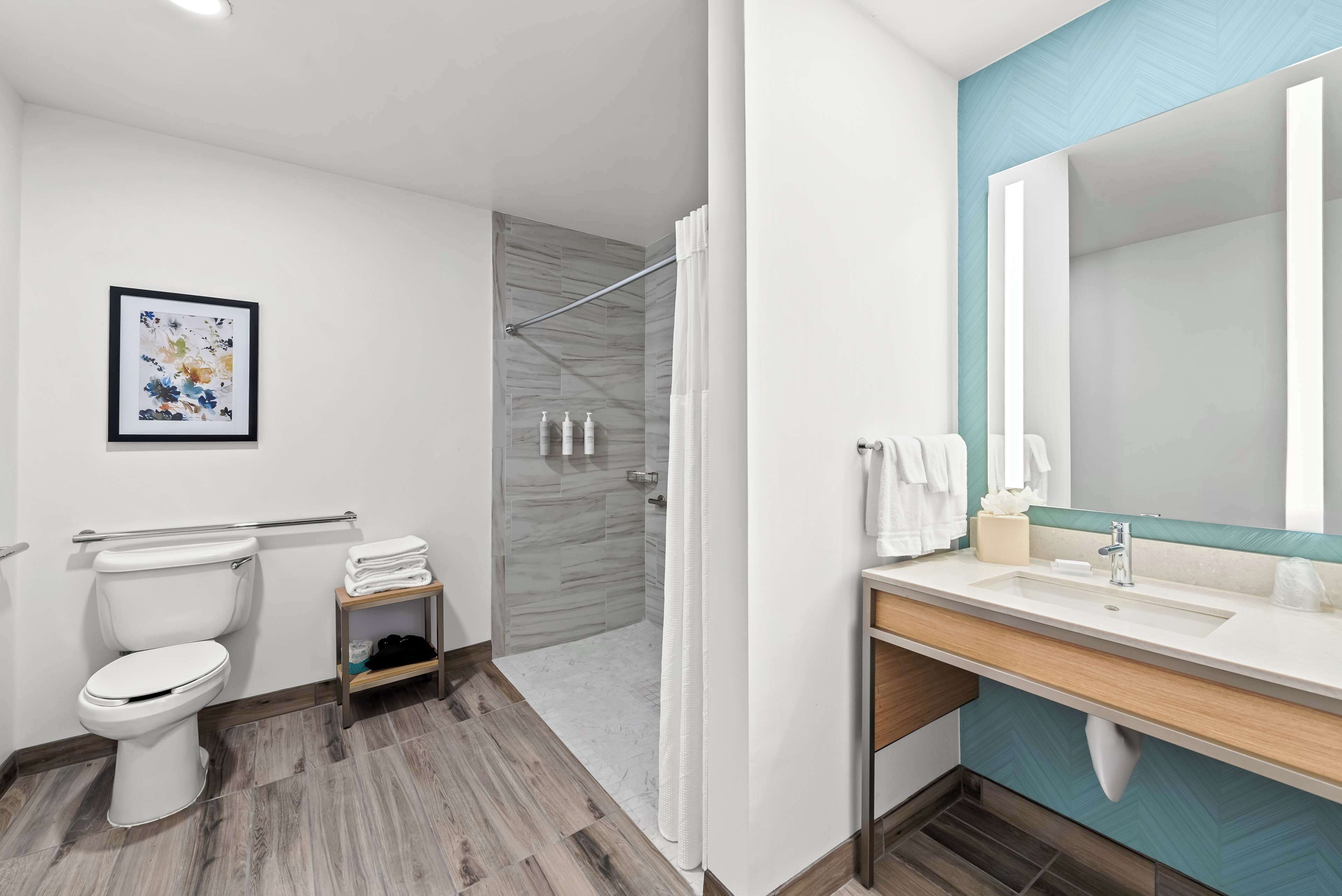 A modern bathroom with a toilet, shower, and sink.