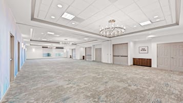Une chambre d’hôtel spacieuse et bien éclairée, dotée d’un grand espace ouvert, de plusieurs portes et d’un lustre.
