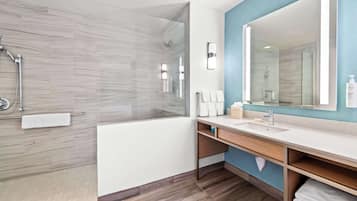 A modern bathroom with a glass-enclosed shower, a large mirror, and a vanity with a sink and towel rack.