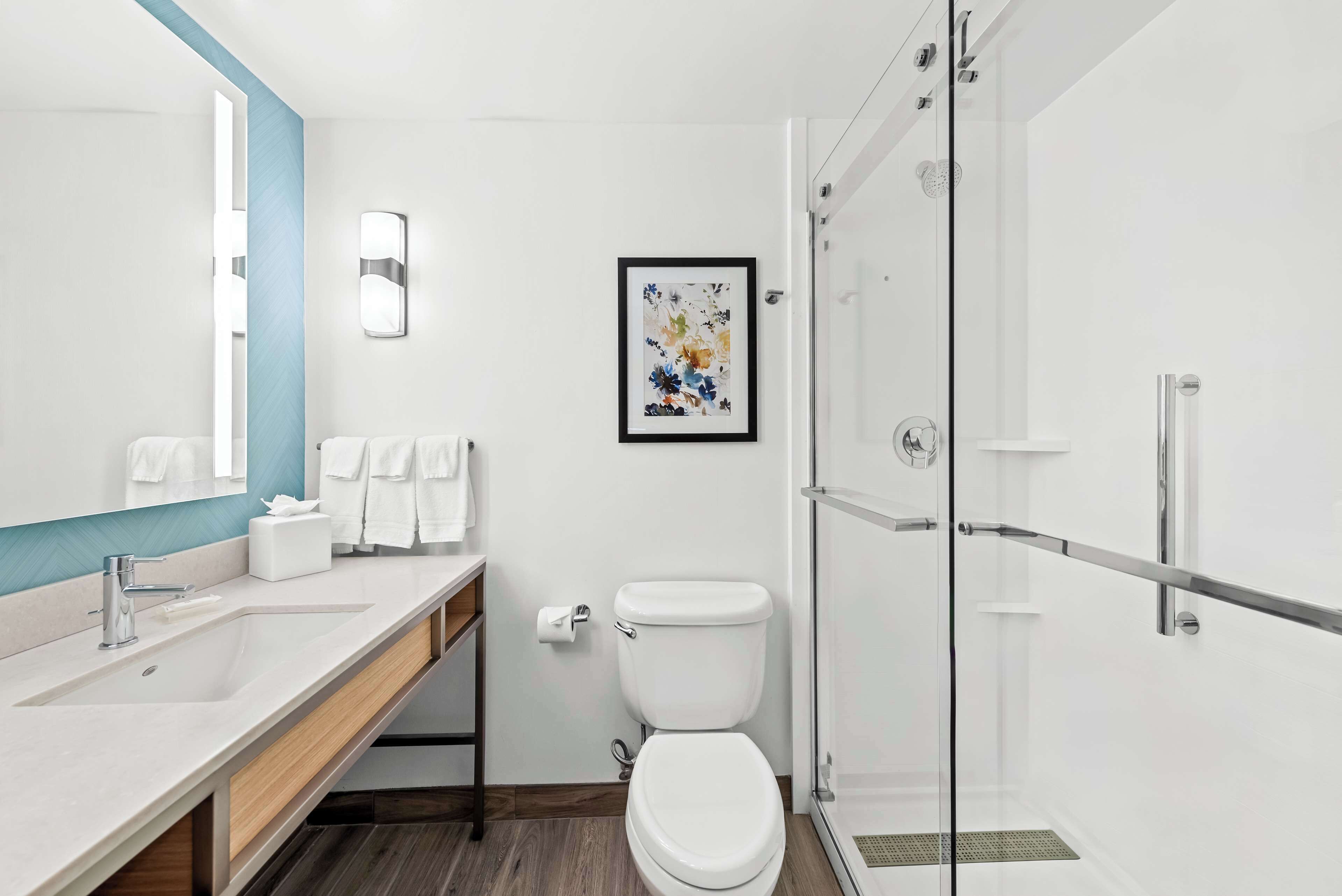 Ein modernes Badezimmer mit einem großen Spiegel, einem Waschbecken, einer Toilette und einer Duschkabine.