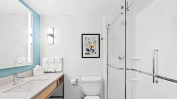 Ein modernes Badezimmer mit einem großen Spiegel, einem Waschbecken, einer Toilette und einer Duschkabine.