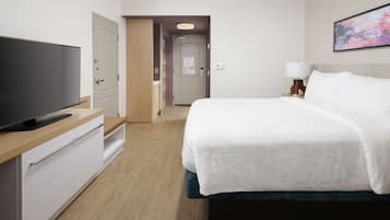 Una habitación de hotel con una cama, un televisor, un escritorio y un cuadro en la pared.