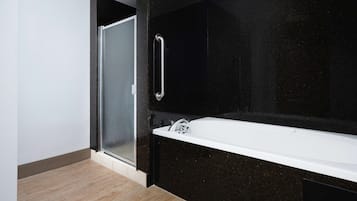 Une salle de bain moderne avec une douche à l’italienne en verre, une baignoire blanche et un mur en marbre noir.