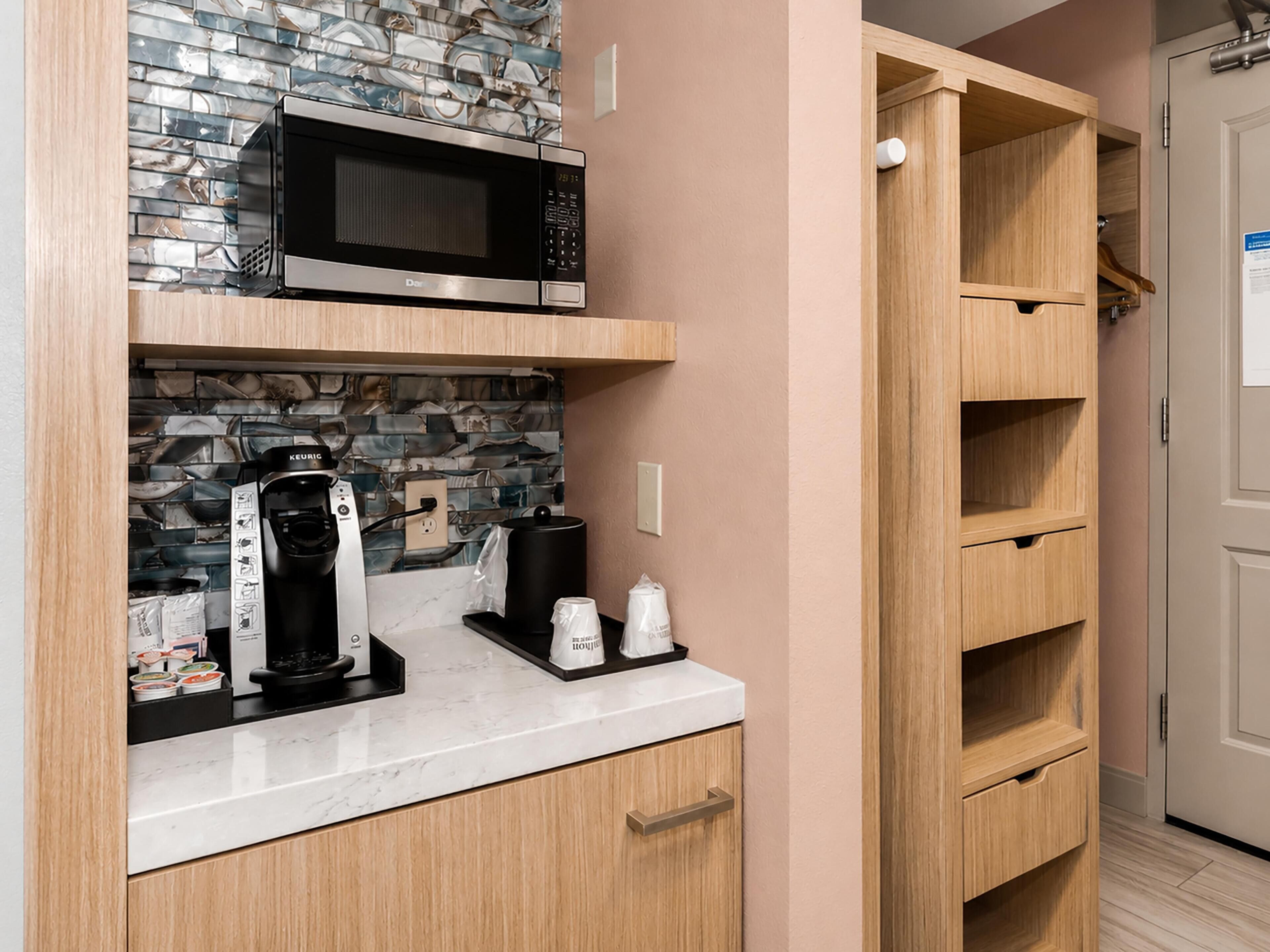 A kitchen with a microwave, coffee maker, and cabinets.