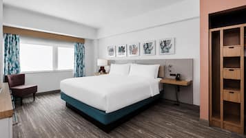Une chambre d’hôtel avec un grand lit, un bureau, une chaise, une armoire et des œuvres d’art accrochées au mur.