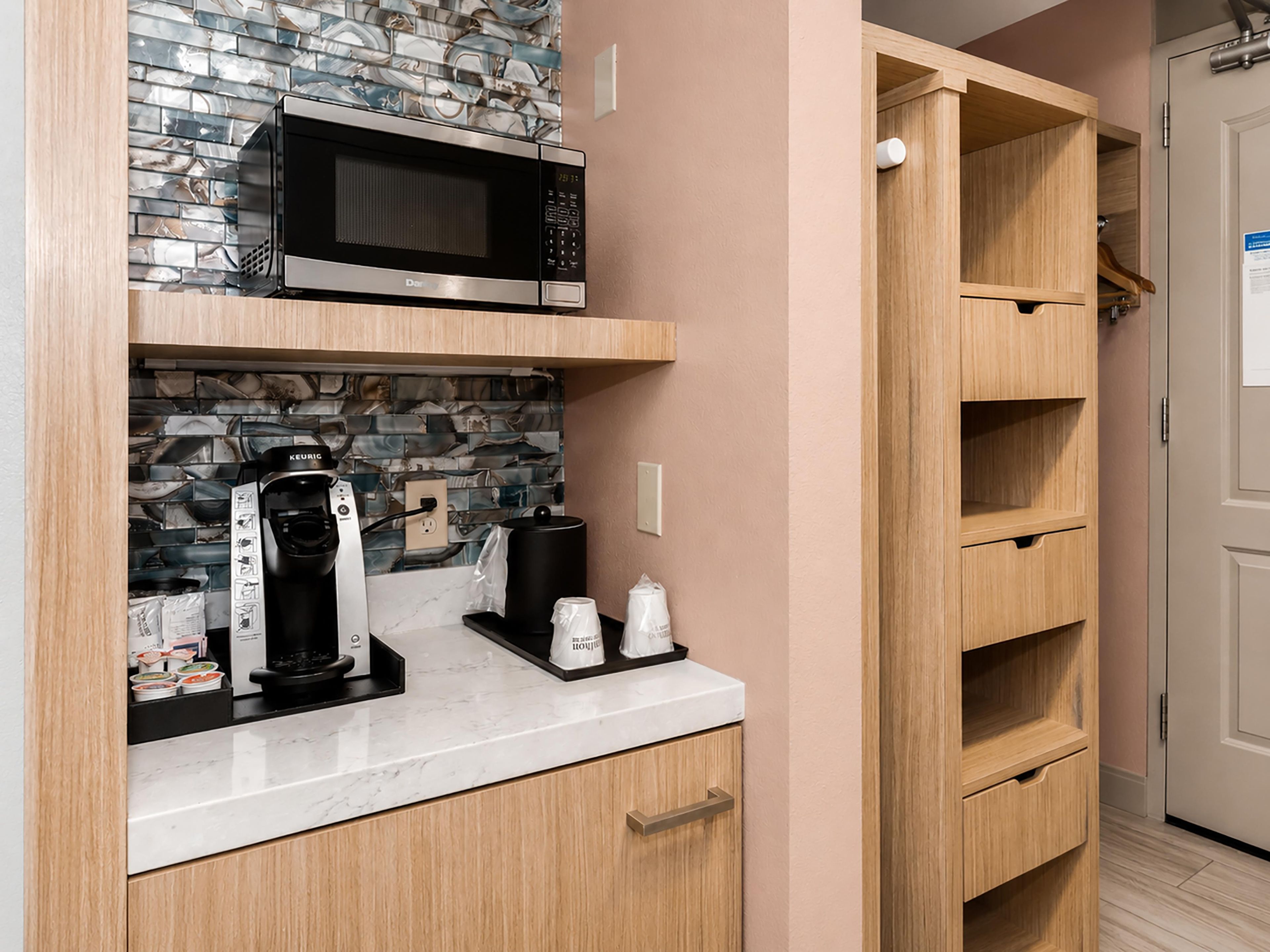 A kitchen with a microwave, coffee maker, and cabinets.
