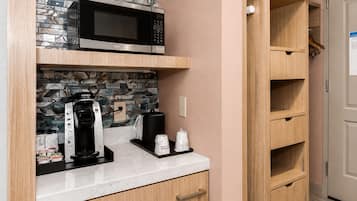 A kitchen with a microwave, coffee maker, and cabinets.