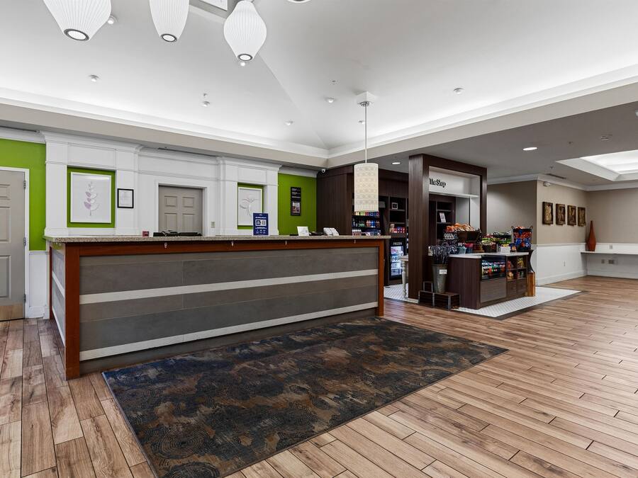 A hotel lobby with a reception desk, a coffee station, and a view of the lobby area.