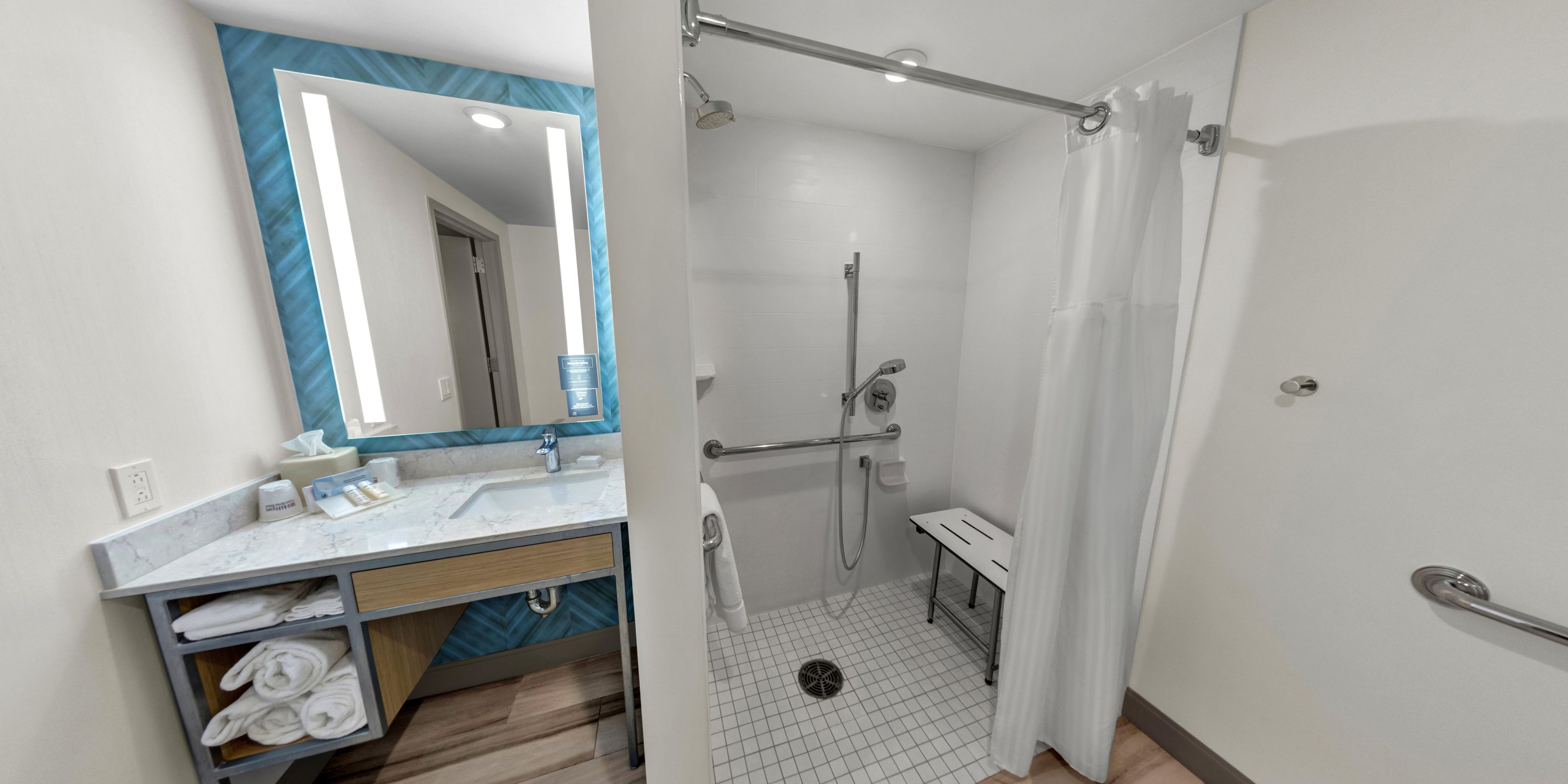 Un baño moderno con ducha, lavamanos y espejo.