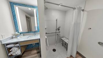 Un baño moderno con ducha, lavamanos y espejo.