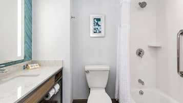 A bathroom with a toilet, shower, and a sink with a mirror.