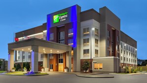 Edificio de Holiday Inn Express & Suites con diseño moderno, destacando un letrero llamativo, una entrada cubierta y un jardín delantero ajardinado.