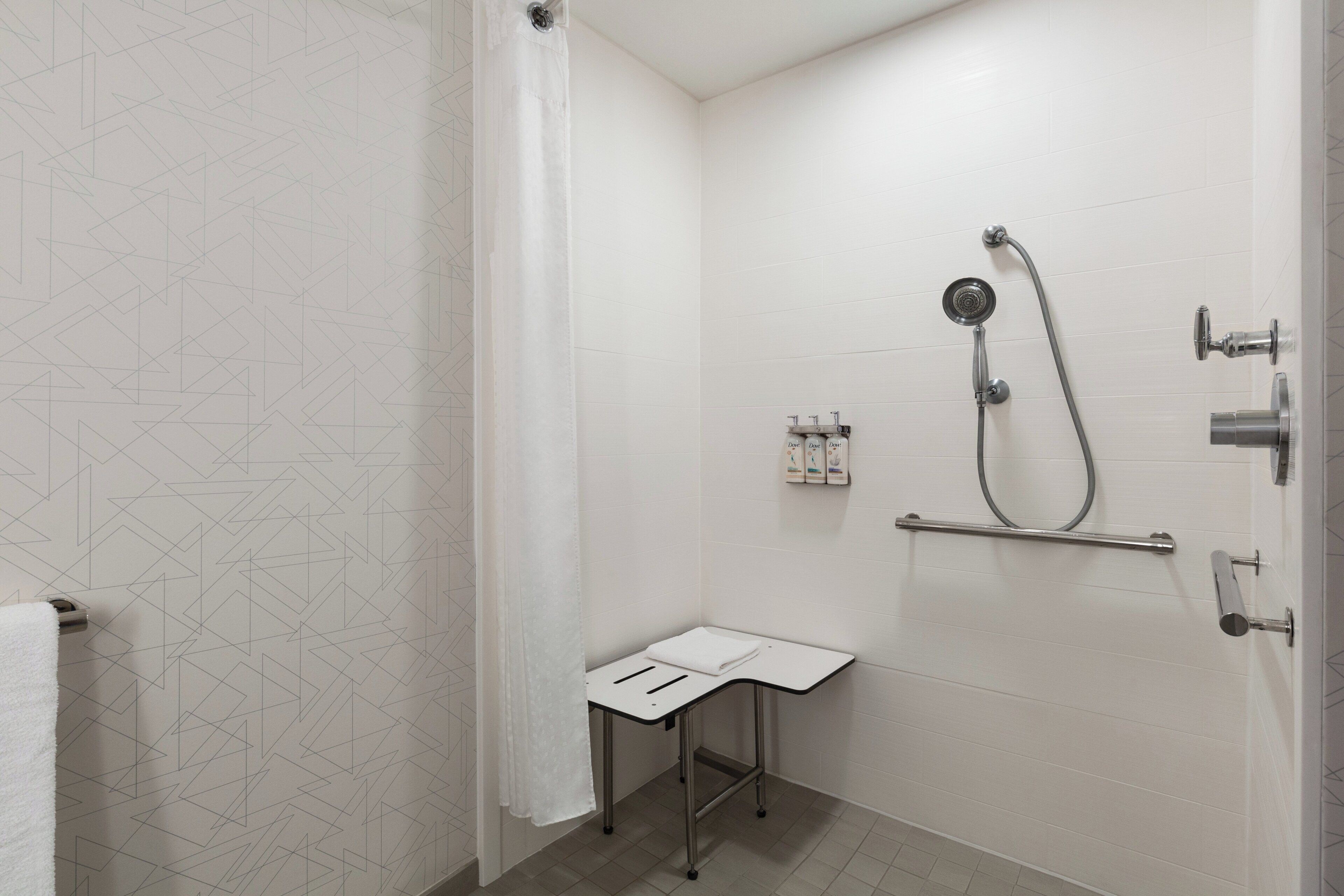 A bathroom with a shower, a towel rack, and a small table.