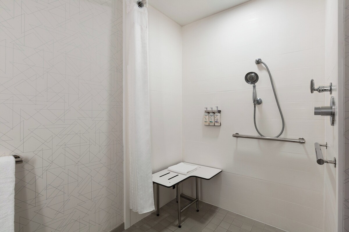 A bathroom with a shower, a towel rack, and a small table.