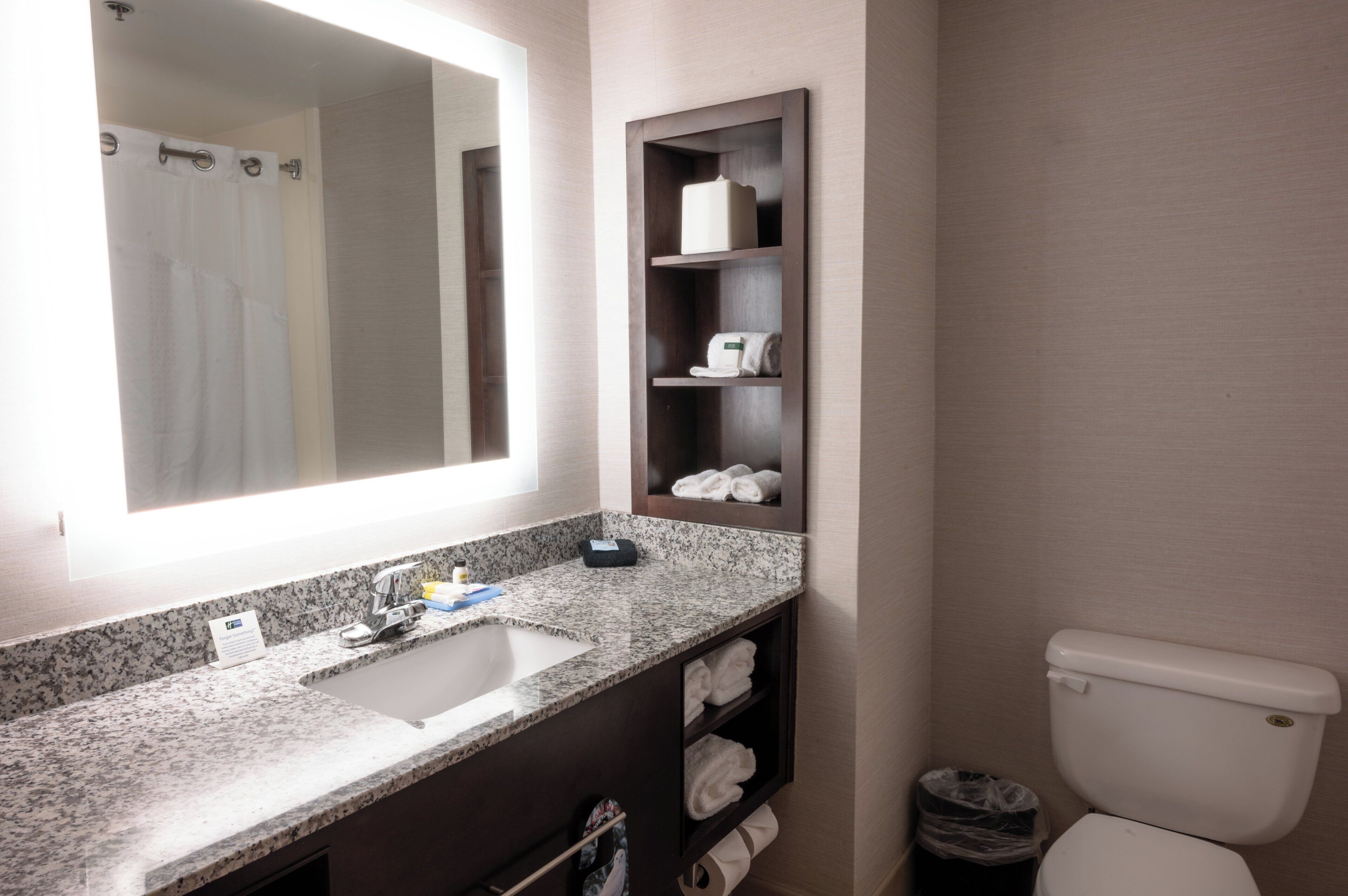 Ein Badezimmer mit Waschbecken, Spiegel, Handtuchhalter und Toilette.