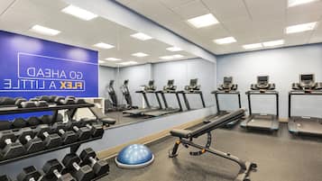 A gym with treadmills, dumbbells, and exercise equipment.
