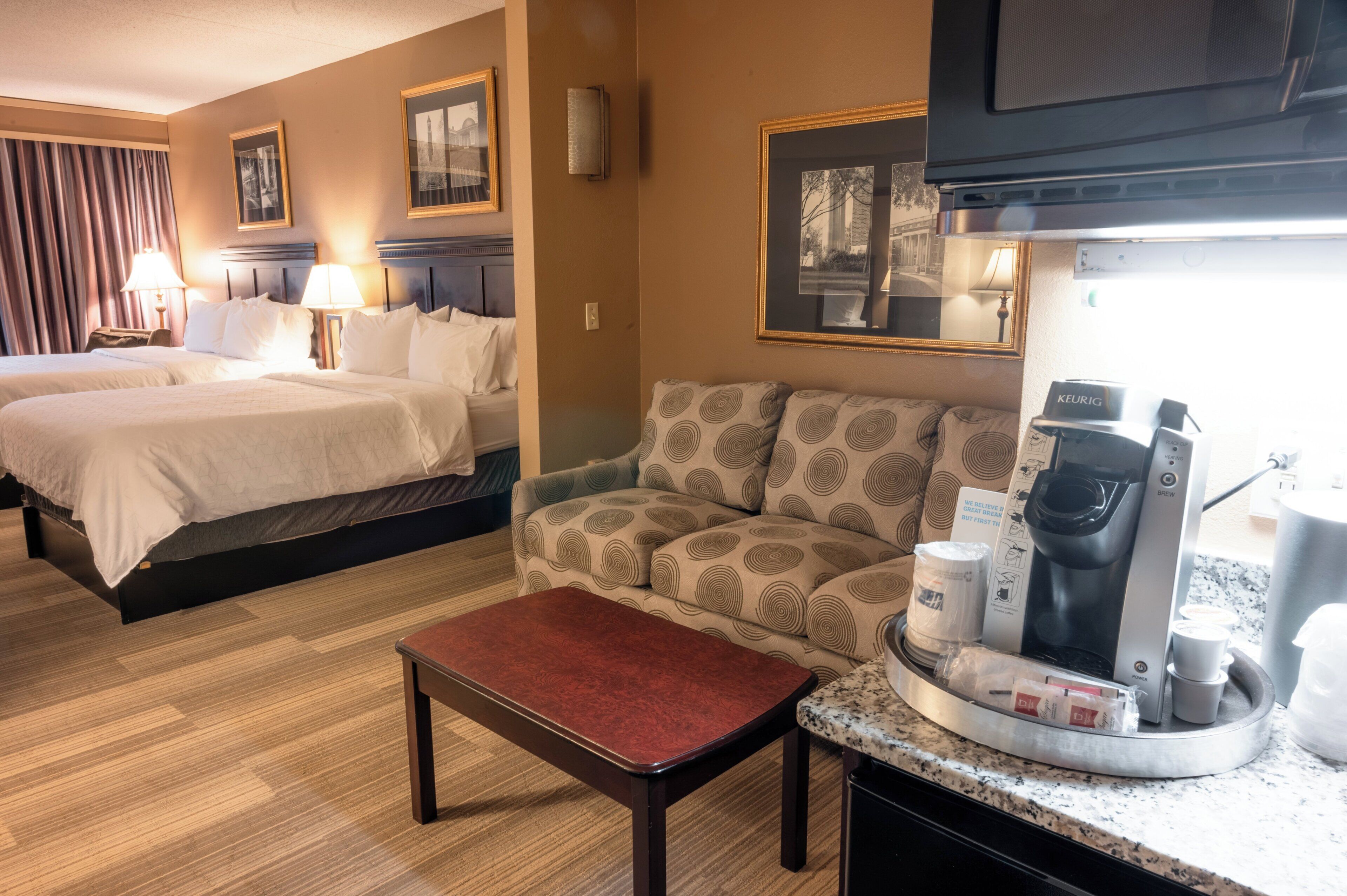 Habitación de hotel con dos camas, un sofá, una zona de café y una mesita.