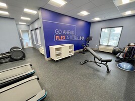 A gym with a blue wall, exercise equipment, and a window.