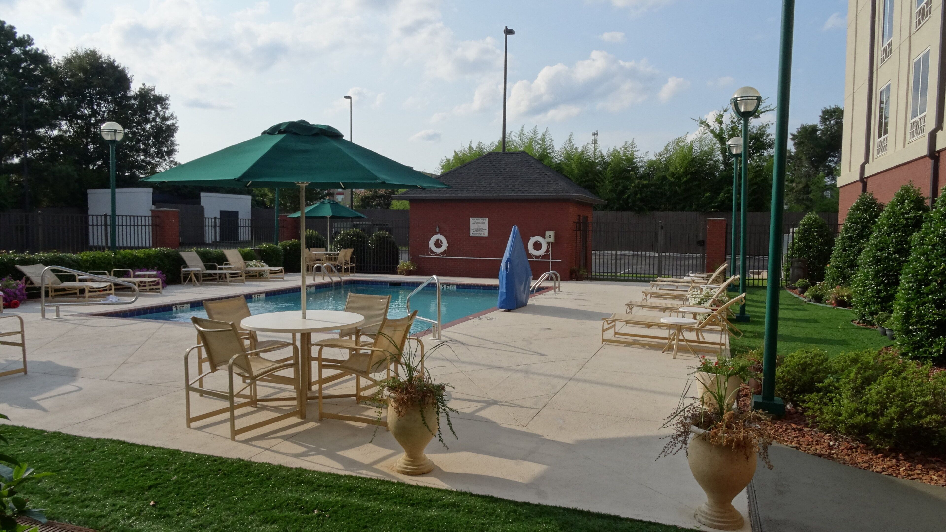 A pool area with lounge chairs, a table, and a covered seating area.
