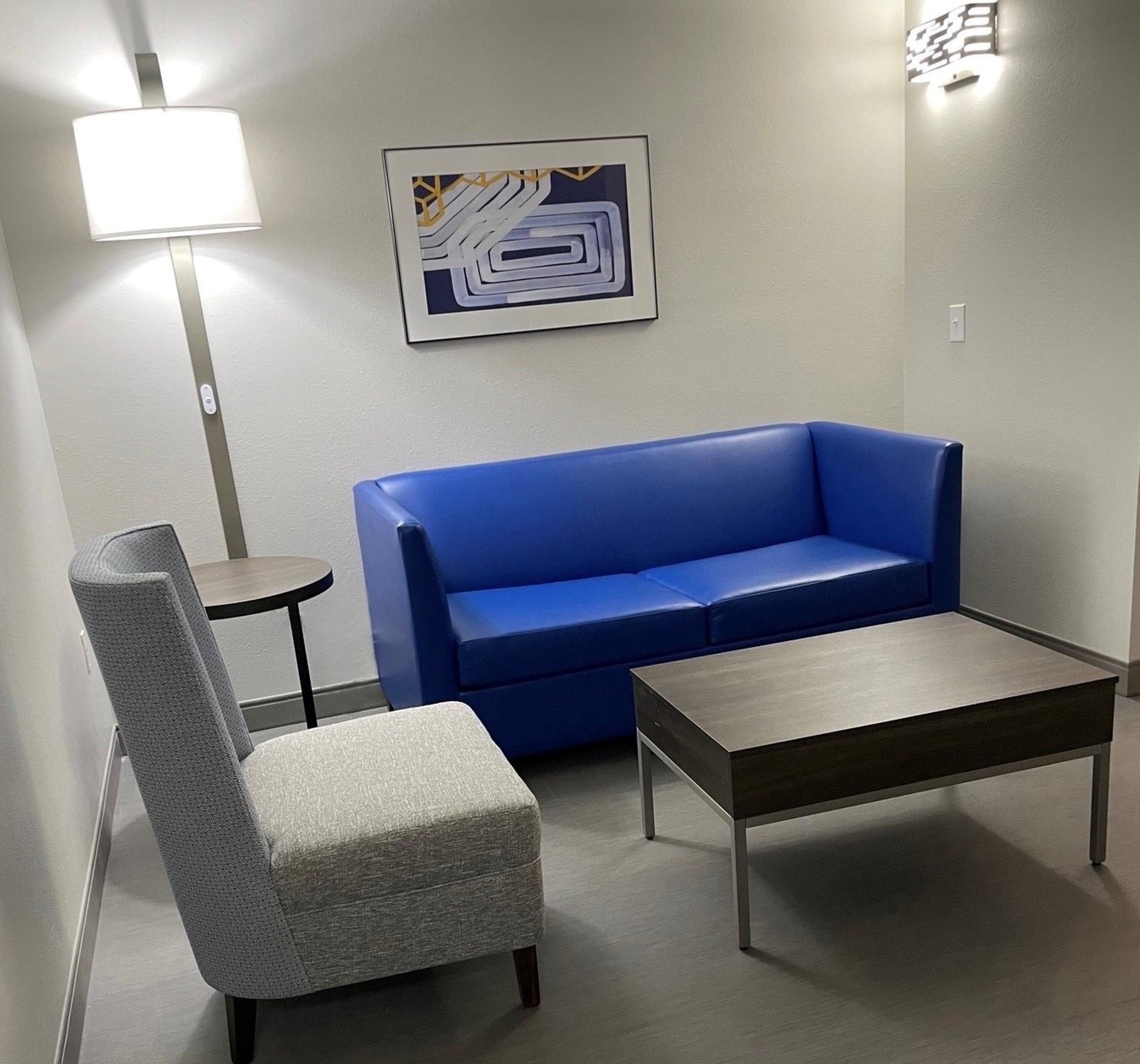 A room with a blue sofa, a grey armchair, and a small table.