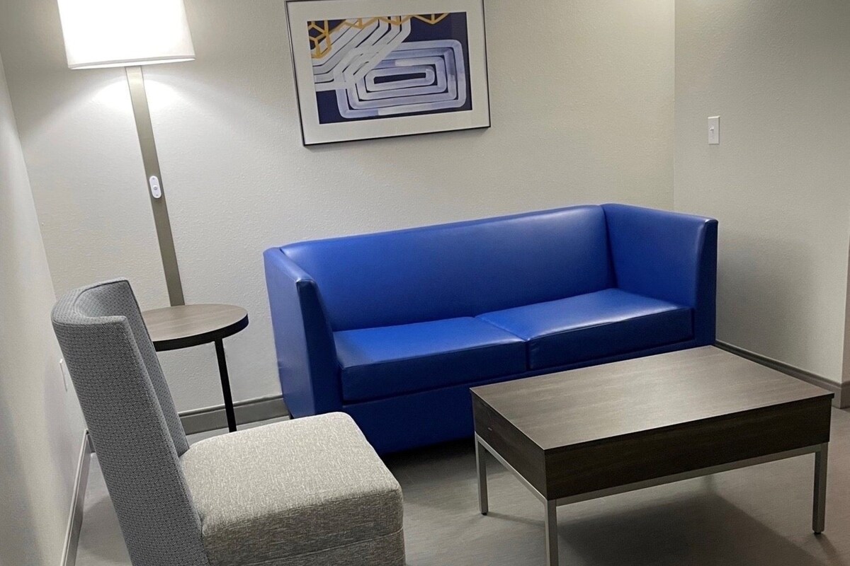 A room with a blue sofa, a grey armchair, and a small table.