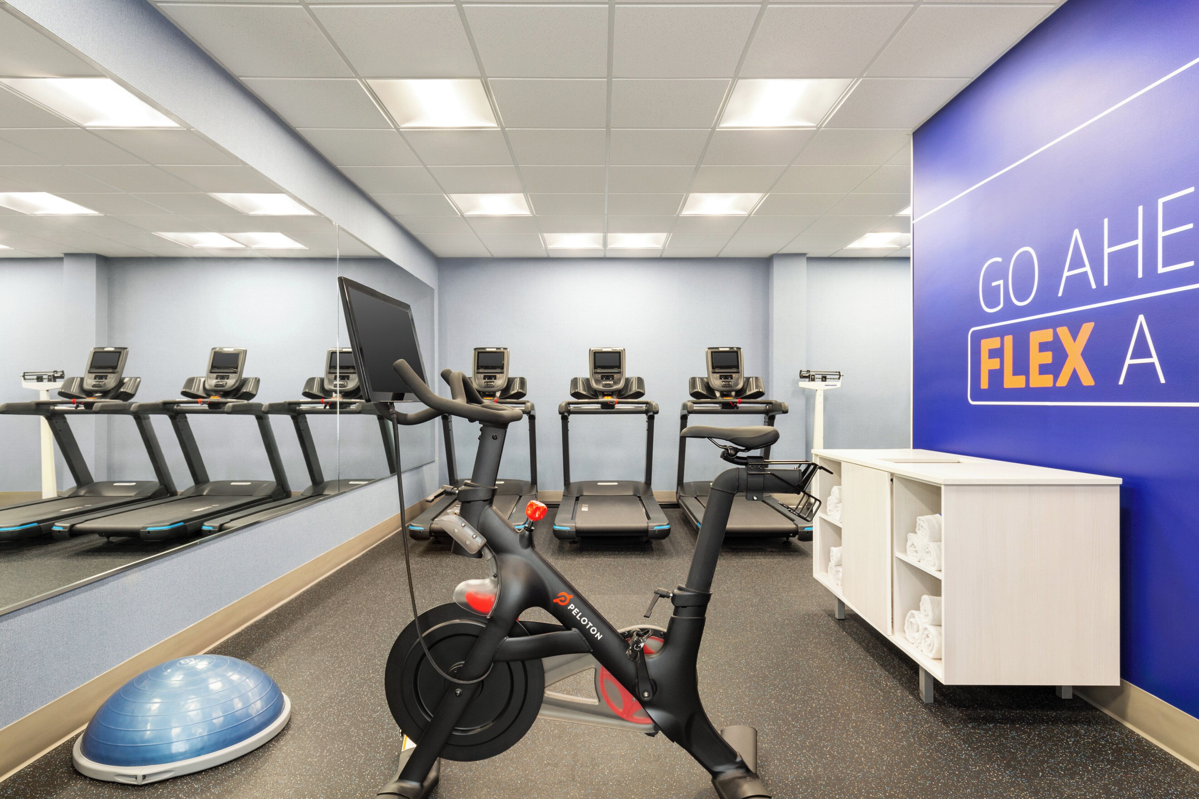 A gym with stationary bikes, treadmills, and a wall with motivational text.