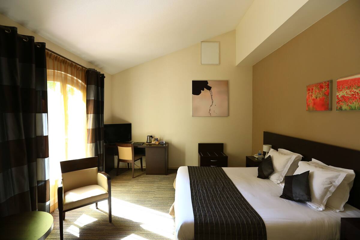 Ein Hotelzimmer mit Bett, Schreibtisch, Stuhl und Fernseher.