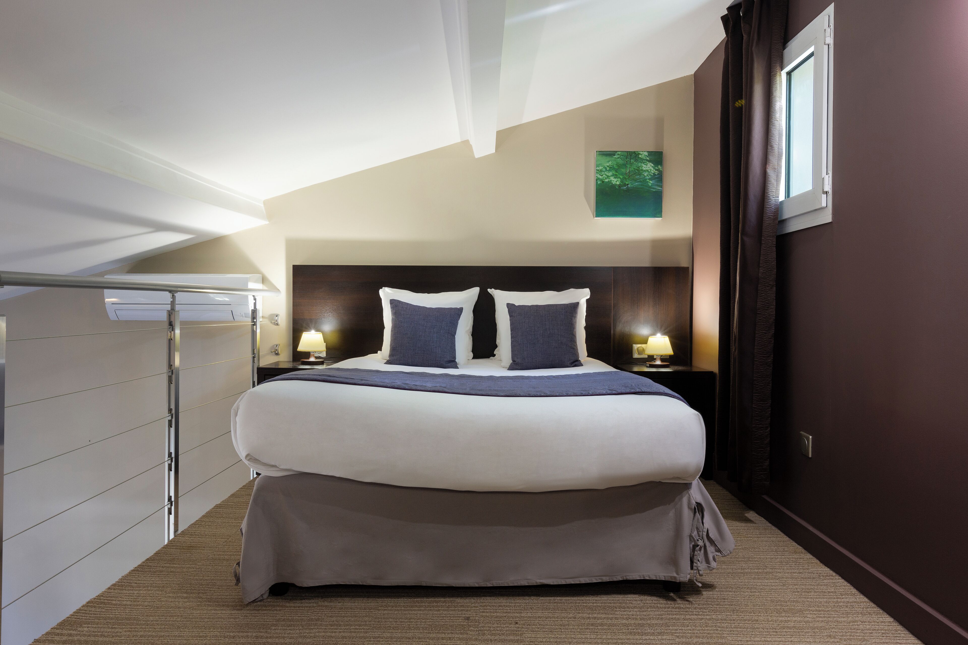 Una habitación de hotel moderna con una cama grande, dos lámparas de noche, un ventilador de techo y una ventana con cortinas.