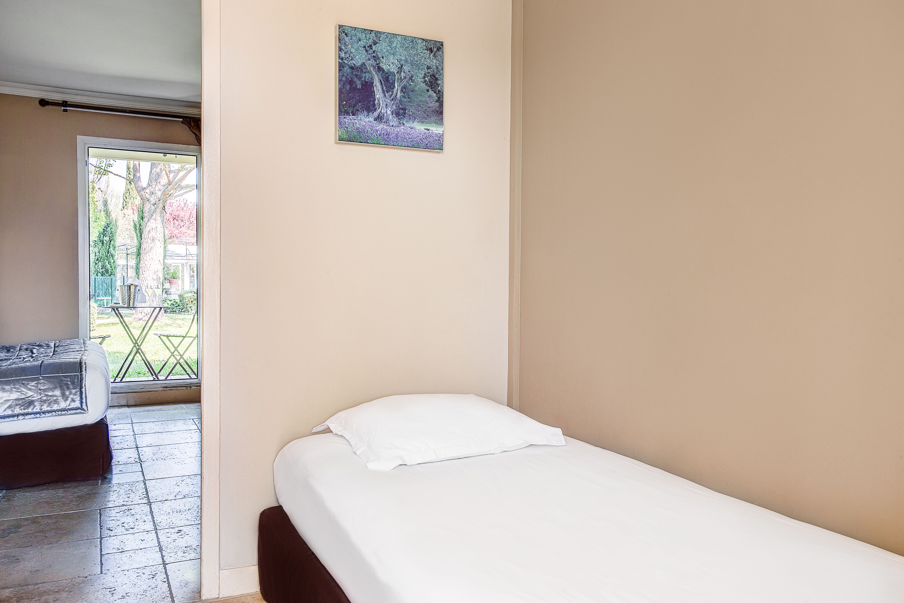 A bedroom with a single bed, a small window, and a door leading to an outdoor area.