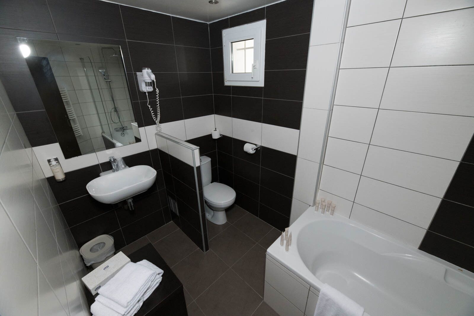 Un baño moderno con un lavamanos, inodoro y bañera blancos.
