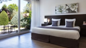 Un dormitorio moderno con una cama grande, vistas al jardín y un comedor con sillas.