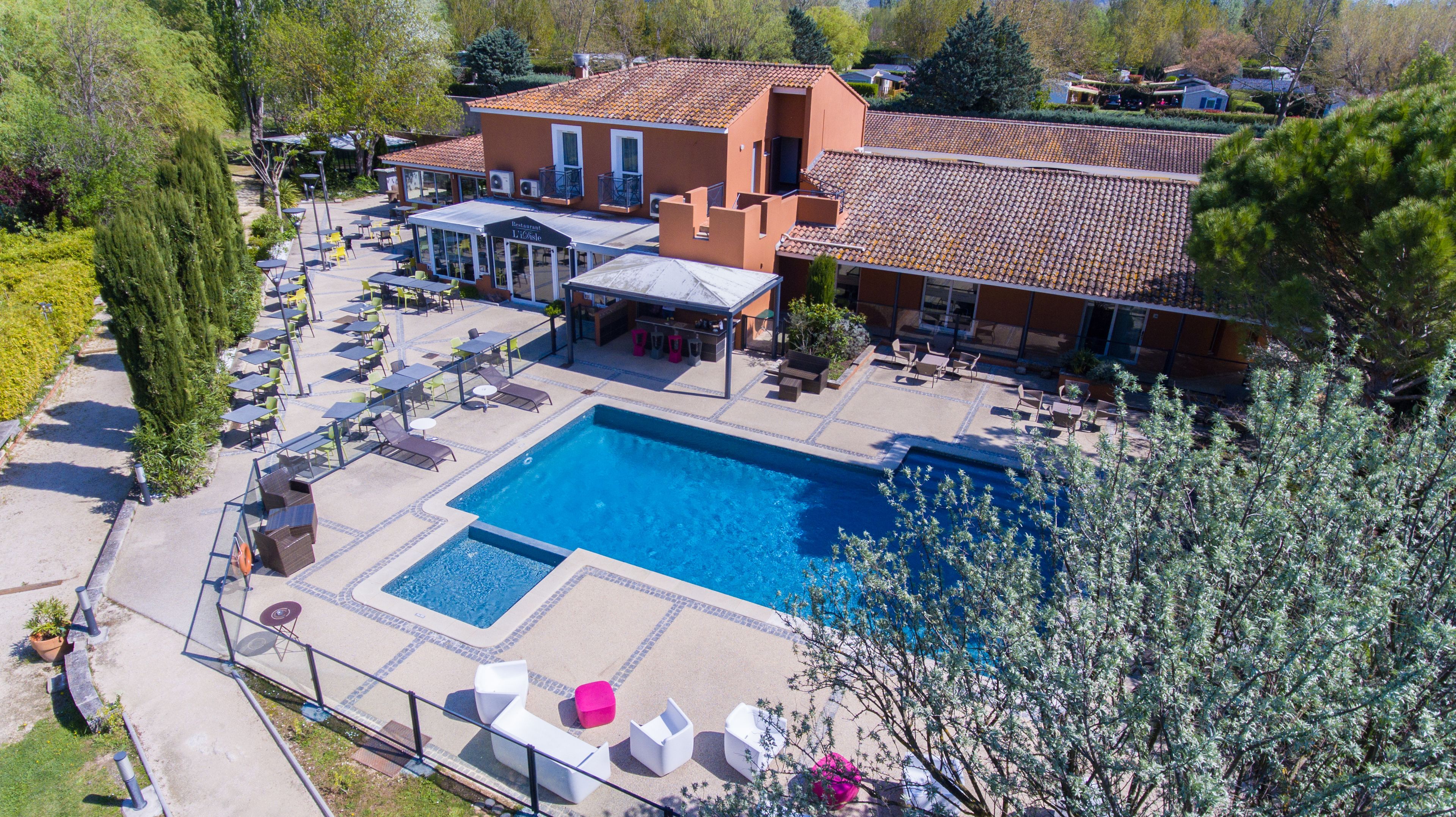 A hotel with a swimming pool, outdoor seating, and a restaurant.