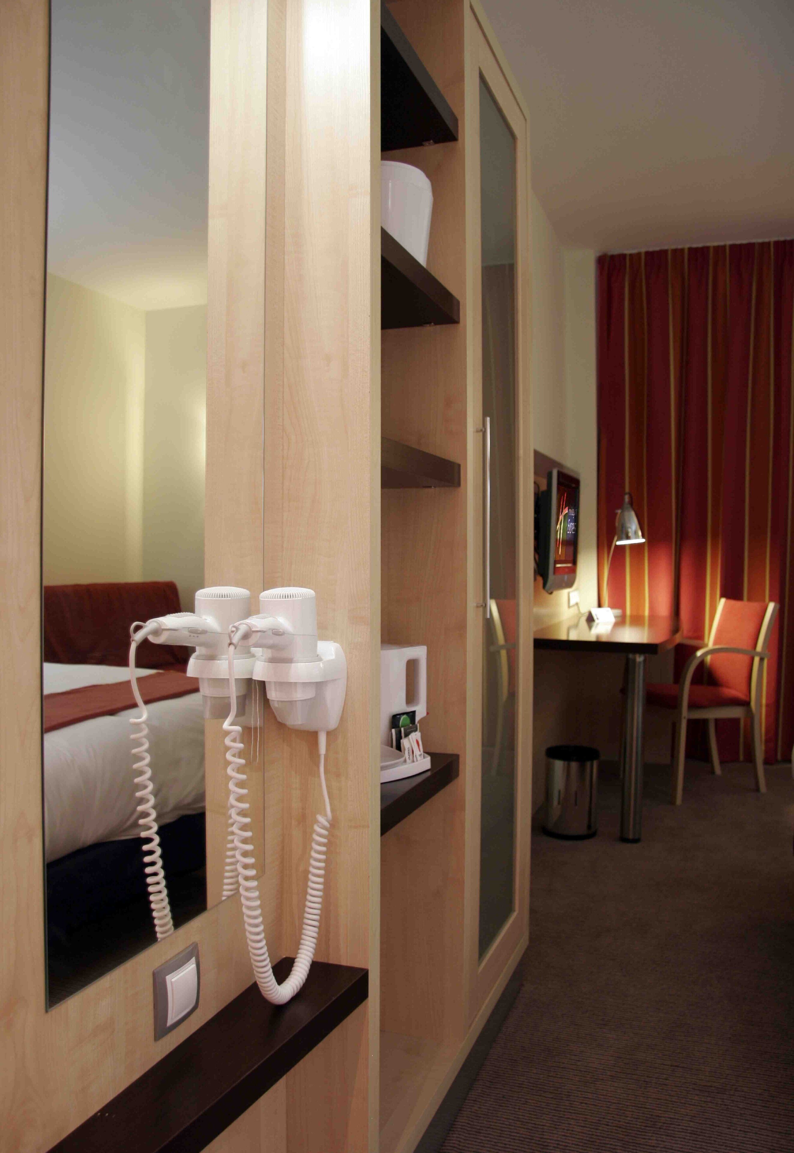 Una camera d'albergo con un letto, una scrivania, una sedia, un telefono e uno specchio.