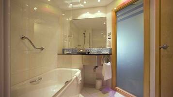 A bathroom with a bathtub, a shower, a sink with a mirror, and a toilet.